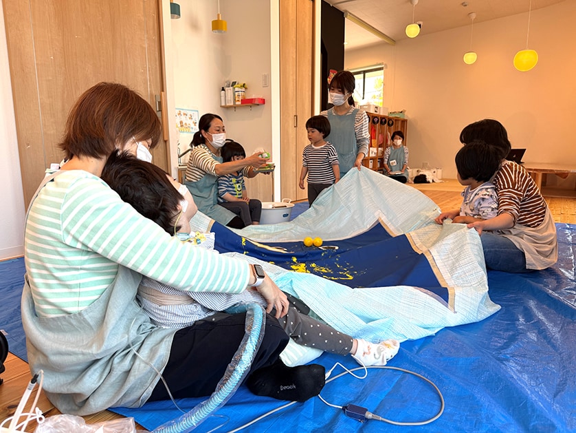 「子どもの日」の前には、みんなで協力しながらペンキのついたボールを転がして鯉のぼりを作成。ふだんは自宅からなかなか外に出られない子どもたちが、集団での遊びを通じて成長できるようサポートしています。