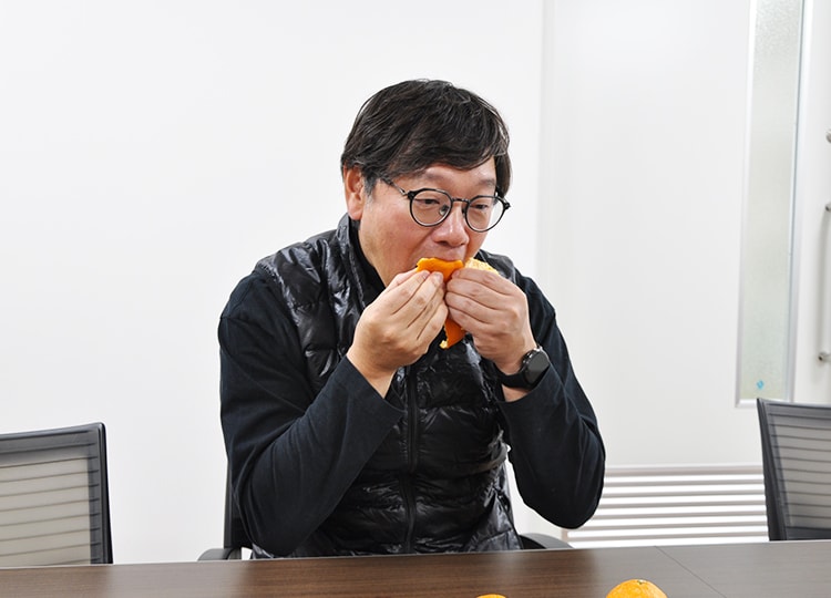 皮にふさがついた状態でみかんを口に運ぶ秋竹社長